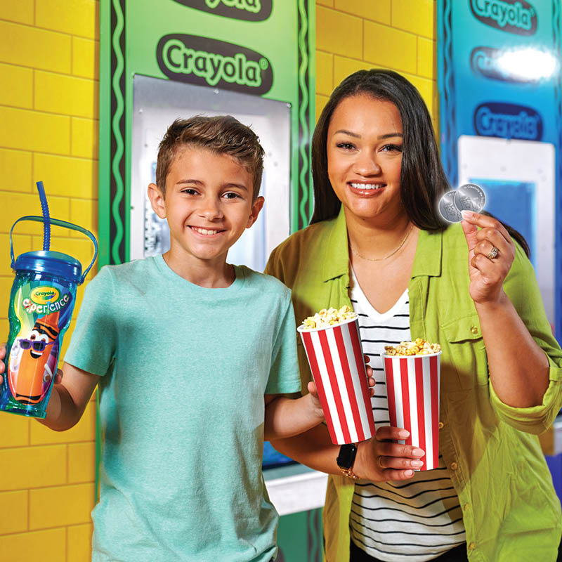 Adult and child holding up a souvenir cup and popcorn